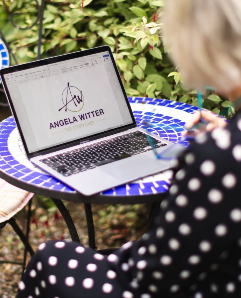A woman looks at a laptop displaying the Story Chefs logo
